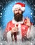 Handsome bearded santa claus man with long beard on serious face holding glass of alcoholic shot in red christmas or
