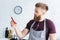 handsome bearded young man in apron and earphones holding chili pepper