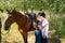 Handsome, beautiful Cowboy and cowgirl couple with horse and saddle on ranch holding and kissing on ranch