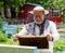 Handsome beekeeper in protective uniform checking the beehive