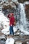 Handsome berded man walking near waterfall at mountains in winter