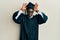 Handsome black man wearing graduation cap and ceremony robe doing bunny ears gesture with hands palms looking cynical and