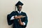 Handsome black man wearing graduation cap and ceremony robe doing time out gesture with hands, frustrated and serious face