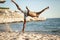 Handsome black young man topless dancing break dance, jumping, handstand, spinning, posing upside down on sand beach .