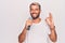 Handsome blond singer man with beard singing song using microphone over white background doing ok sign with fingers, smiling