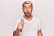 Handsome blond singer man with beard singing song using microphone over white background scared and amazed with open mouth for