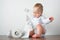 Handsome blonde toddler in shirt and toilet paper rolls with potty. Potty training