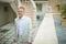 Handsome and blondy groom walking to brides room across terrace.