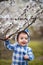 Handsome boy clings to a branch in the garden. Boy in dlue teddy bear costume with flowers