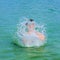 handsome boy enjoys sputtering with his hand in the tropical ocean