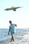 Handsome boy in shorts and a t-shirt teenager launches a kite on the sky on the seashore