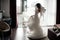 Handsome bride in white dress and veil dancing near the window