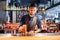 Handsome brunette barista of East Caucasian appearance preparing a drink at the bar in a restaurant. Mixing a coffee and orange