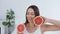 Handsome brunette woman posing with two half of grapefruit.