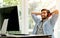 Handsome business man with casual cloth is listening some music from computer in front of the computer in glass window room of his