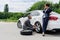handsome businessman changing tires on car on road businesswoman talking