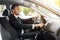Handsome businessman driving car to airport, turning on music