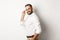 Handsome businessman turn at camera and looking confident, smiling cheeky, standing over white background