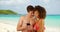 Handsome Caucasian male with female friend using smartphone on beach.