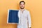 Handsome caucasian man with beard holding photovoltaic solar panel looking positive and happy standing and smiling with a