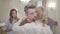 Handsome Caucasian man giving bouquet of violet roses to blond woman and hugging her. Guy showing annoyed facial