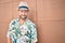 Handsome caucasian man wearing summer hat and flowers shirt smiling happy outdoors