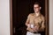 Handsome caucasian stylish guy in brown shirt posing, standing near window with cup of coffee