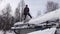 Handsome Caucasian teenager in grey blue jacket with shovel remove snow from roof of totally snow covered house, cabin in