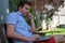 Handsome caucasian young man working on laptop and smiling while sitting outdoors. Concept of self employer.