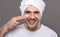 Handsome cheerful man cares about beauty with towel on head