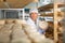 Handsome cheese maker checking aging process of goat cheese standing at small cellar.