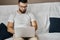 Handsome clever man in glasses sitting with laptop on sofa