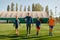 Handsome coach and junior soccer team walking across field