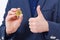 Handsome confident businessman holding gold bitcoin coin. Selective focus. Business success concept. Big thumb up.