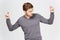 Handsome confident man in grey pullover dancing with raised hands