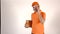 Handsome courier in orange uniform talking on his mobile phone and delivering a parcel. Light grey backround, 4K studio