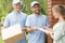 Handsome couriers in blue uniforms delivering a parcel to a young pretty woman