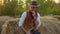 Handsome cowboy posing near hay on his farm