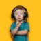 Handsome cute blonde little boy three years old in gaming black headphones. look at camera, grey eyes and grey t-shirt on yellow