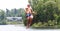 Handsome cute man jumping at a water trampoline floating in a lake in Michigan during summer.