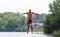 Handsome cute man jumping at a water trampoline floating in a lake in Michigan during summer.