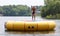 Handsome cute man jumping at a water trampoline floating in a lake in Michigan during summer.