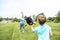 Handsome dad with his little cute sun are playing baseball on green grassy lawn