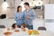 Handsome delighted little boy looking at her sister and having healthy breakfast with their parents on background