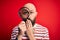 Handsome detective bald man with beard using magnifying glass over red background cover mouth with hand shocked with shame for