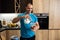 Handsome dude adding milk to his fruit shake while chilling in his apartment, healthy eating