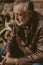 Handsome elderly man in leather cap sits in yard