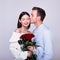 Handsome elegant guy is giving roses to his beautiful girlfriend and kissing her