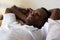 Handsome ethnic black african man resting in bed sleeping or napping.