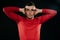 Handsome European sportsman wearing red sportswear and posing after hard exercise on dark background. Sporty man stretching with h